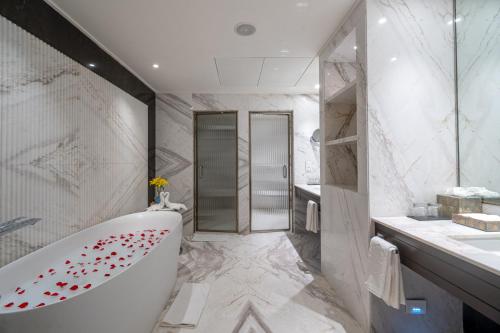 a white bathroom with a tub and a sink at Taj Deccan in Hyderabad