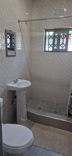 a white bathroom with a sink and a toilet at Salama Apartments in Lusaka