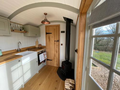 a kitchen with a stove in a tiny house at Private and peaceful stay in a Luxury Shepherds Hut near Truro in Truro