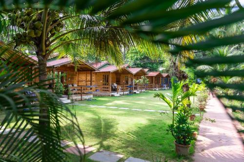 a row of wooden huts in a yard with palm trees at Rockit Cafe & Stay in Palolem