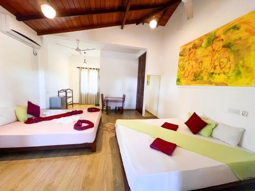 a room with two beds and a table in it at Villa Red Lobster in Hikkaduwa