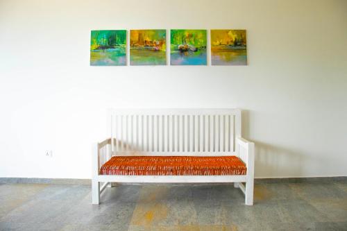 a white bench sitting in front of a wall with paintings at Villa Red Lobster in Hikkaduwa