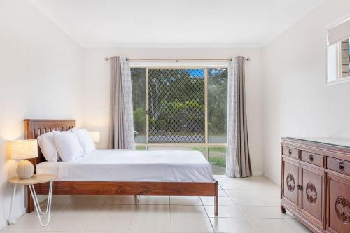 a bedroom with a bed and a large window at Bay Breeze - Easygoing Beachside Living for Families in Hervey Bay