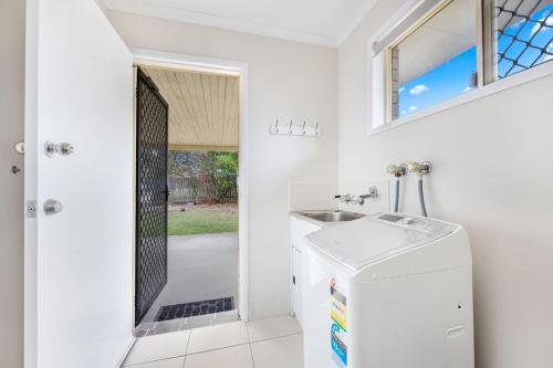 a white bathroom with a sink and a refrigerator at Bay Breeze - Easygoing Beachside Living for Families in Hervey Bay