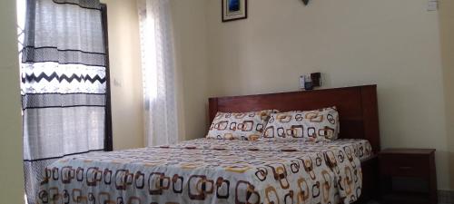ein Schlafzimmer mit einem Bett mit einer Decke und einem Fenster in der Unterkunft ADOUFE in Cotonou