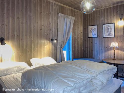 een slaapkamer met een wit bed en een houten muur bij Hafjelltunet in Hafjell