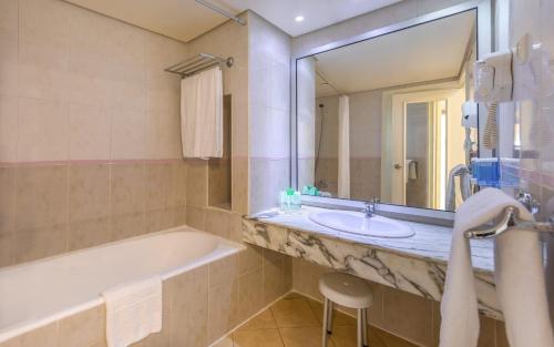 y baño con bañera, lavabo y espejo. en Hotel Marhaba Beach en Sousse