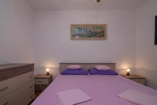 a bedroom with a large bed with purple pillows at Sandra A2+1*** in Veli Lošinj