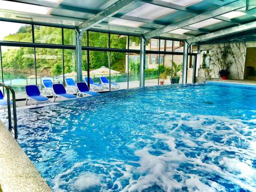 una gran piscina con sillas azules. en Kamelot Hotel, en Pasarel