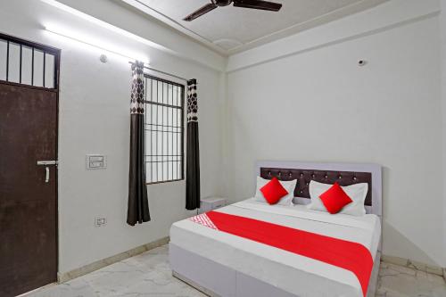 1 dormitorio con 1 cama con almohadas rojas y blancas en OYO 81321 Flagship Golden Crest Inn, en Noida