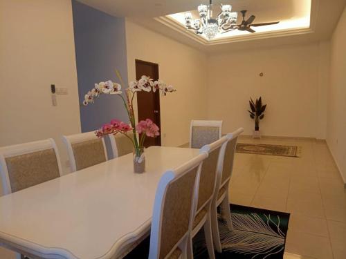 un comedor con una mesa blanca con flores. en Homestay Al Qamar Kempadang, en Kuantan