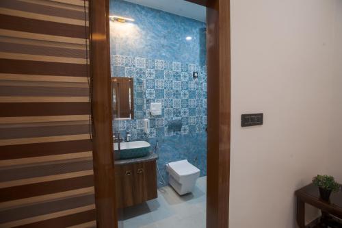 a bathroom with a sink and a toilet with blue tiles at Madhav Residency in Mathura