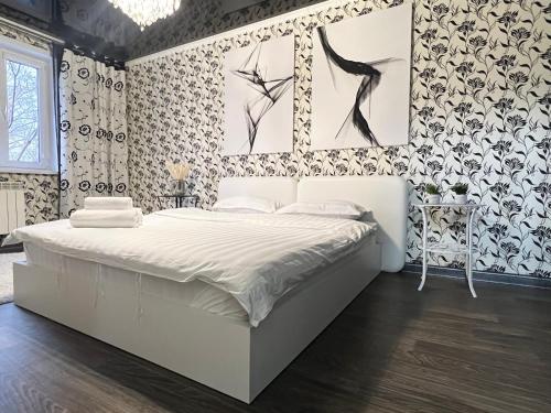 een slaapkamer met een groot wit bed met bloemenbehang bij Уютная Квартира с ванной. in Pavlodar