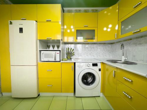 a yellow kitchen with a refrigerator and a washing machine at Уютная Квартира с ванной. in Pavlodar