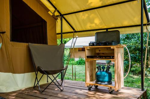 a tent with a chair and a table and a kettle at CAMPING ONLYCAMP DES HALLES in Decize