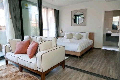 een slaapkamer met een bed, een bank en een stoel bij The Deck Patong in Patong Beach