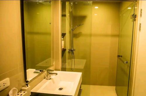 een badkamer met een wastafel en een douche met een spiegel bij The Deck Patong in Patong Beach