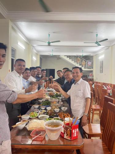 un grupo de hombres parados alrededor de una mesa con comida en Hotel Thi Hoa Bái Đính, en Tiên Tân
