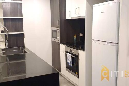 a kitchen with a white refrigerator and a stove at Delight in Dickson -2bd 2bth 2Csp Apt in Canberra
