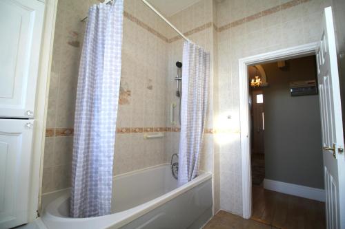Large 3 Bed Bungalow - Beautiful Refurb - Garden في برمنغهام: حمام مع حوض استحمام ودش مع ستارة الدوش