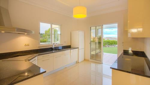 a large kitchen with white cabinets and a refrigerator at Villas @ Quinta do Vale Golfe in Castro Marim