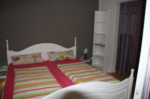 a bed with a striped blanket and pillows in a bedroom at Ferienwohnung Klint 2 in Dellstedt