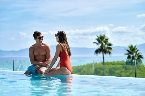 un hombre y una mujer sentados en una piscina en Iberostar Selection Albufera Playa All Inclusive en Playa de Muro