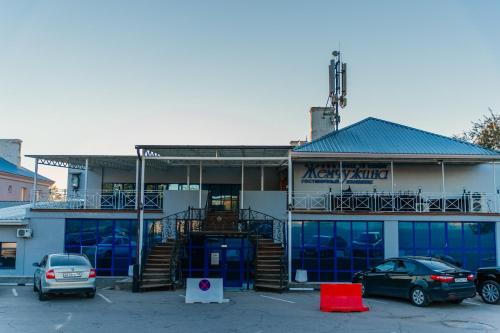 a building with a car parked in a parking lot at Жемчужина гостиница Балхаш in Balqash