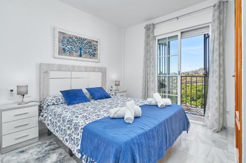 een slaapkamer met een bed met blauwe lakens en een raam bij Casa Sócrates in Nerja