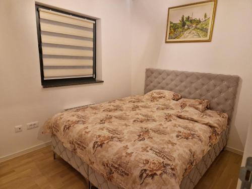 una cama en un dormitorio con ventana en Apartman BJELA, en Bjelašnica