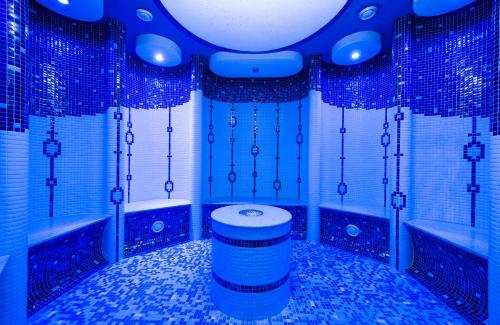 La salle de bains est pourvue de murs carrelés bleus et de toilettes. dans l'établissement Hotel Polovnik, à Demänovská Dolina