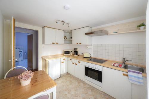 a kitchen with white cabinets and a wooden table at Wohnung am Kurpark in Lippstadt
