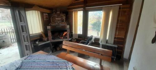 a bedroom with a fireplace and a bench and windows at Krushka, Kochani, Osogovo in Kočani