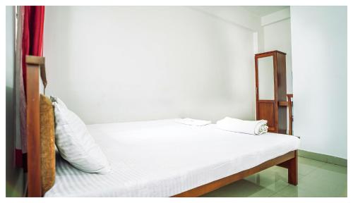 een slaapkamer met een wit bed en een houten frame bij Kay Kay Residency in Cochin