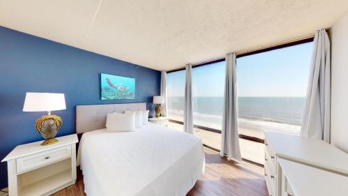 een slaapkamer met een bed en een groot raam met uitzicht op de oceaan bij Willow Bay Resort in Myrtle Beach