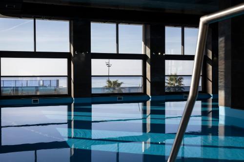 einen Pool mit Fenstern und blauem Wasser in der Unterkunft Green Side Apart Hotel in Batumi