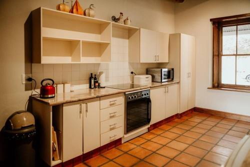 a kitchen with white cabinets and a stove top oven at Die Stal at Antioch in Franschhoek