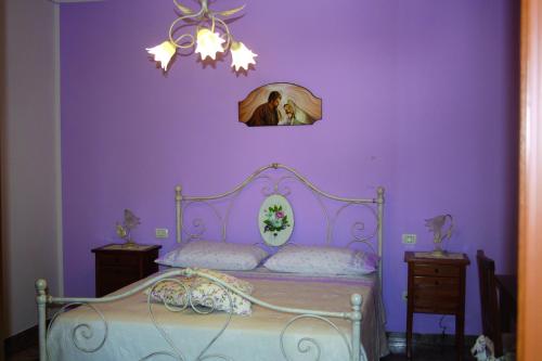 a purple bedroom with a bed and a chandelier at Il Podere di Francesco in Rivotorto 