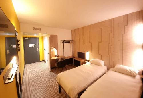 una camera d'albergo con 2 letti e una scrivania di B&B HOTEL Nice Stade Riviera a Nizza