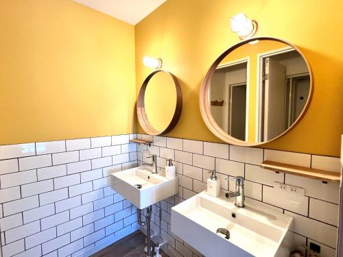 a bathroom with two sinks and two mirrors at Hostel Coliberty in Tokushima