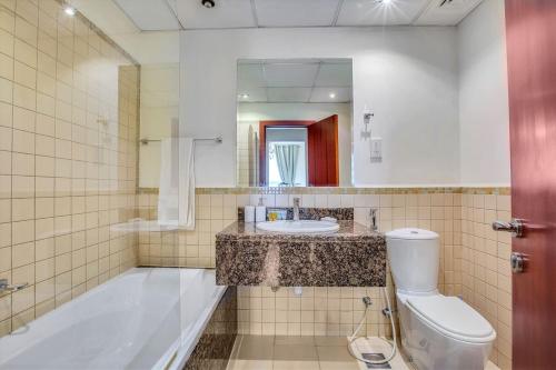 a bathroom with a sink and a tub and a toilet at Bright apartment on the JBR Beach in Dubai