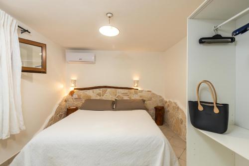 1 dormitorio con cama blanca y bolsa negra en GRECALE a pochi passi dal mare, en Santa Maria Navarrese
