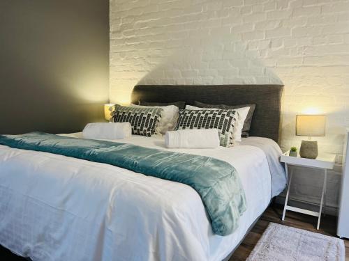 una gran cama blanca con almohadas encima en The Charming Place, en Ciudad del Cabo