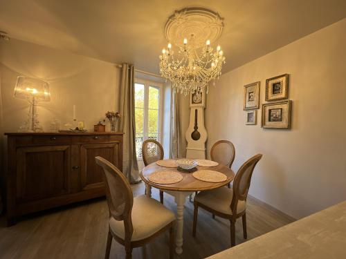 a dining room with a table and chairs and a chandelier at Babolène Shabby Suite in Villefranche-de-Rouergue