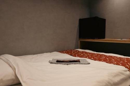 a white bed with a shirt and a television on it at 万雷ホテル in Tokyo