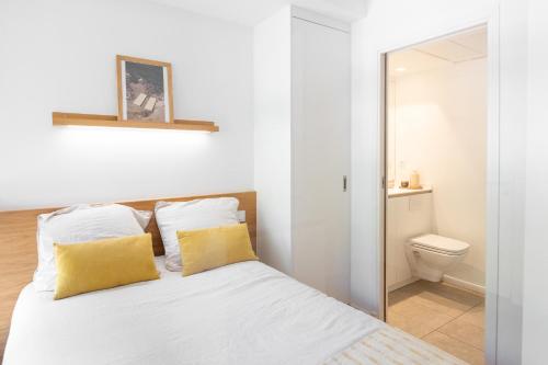 a bedroom with a bed with yellow pillows and a toilet at Les appartements de Montpellier in Montpellier