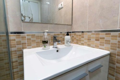 ein Badezimmer mit einem weißen Waschbecken und einem Spiegel in der Unterkunft rentafive Nuevo Barbacoa Terraza Playa in Gran Alacant