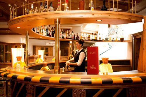 a woman standing behind a bar in a restaurant at Wellnesshotel Parkschlössl zu Thyrnau Ihr adults only SPA Resort in Thyrnau