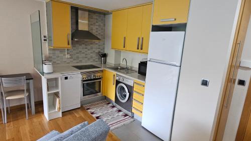 a kitchen with yellow cabinets and a white refrigerator at Ladeira in Baiona