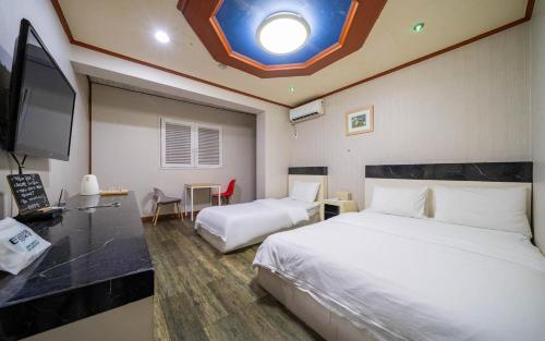 a hotel room with two beds and a flat screen tv at Sokcho Time Hotel in Sokcho